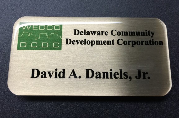 Brushed gold nametag with epoxy coating. Design for Delaware Community Development Corporation.