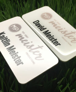 Photo of two plastic nametags. One with epoxy coating. Design for Meister Productions.