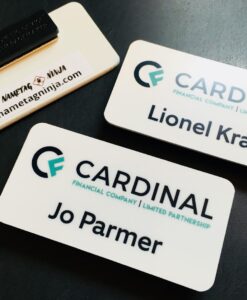 A collection of white plastic nametags, photo showing front and back of the product. Logo is for Cardinal Financial Company.
