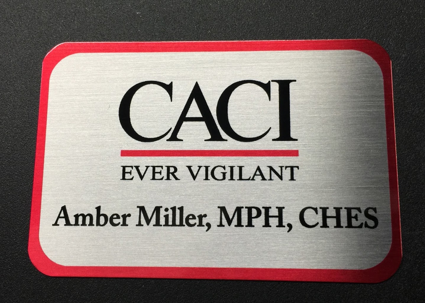 A brushed silver name badge. Design for CACI Ever Vigilant.