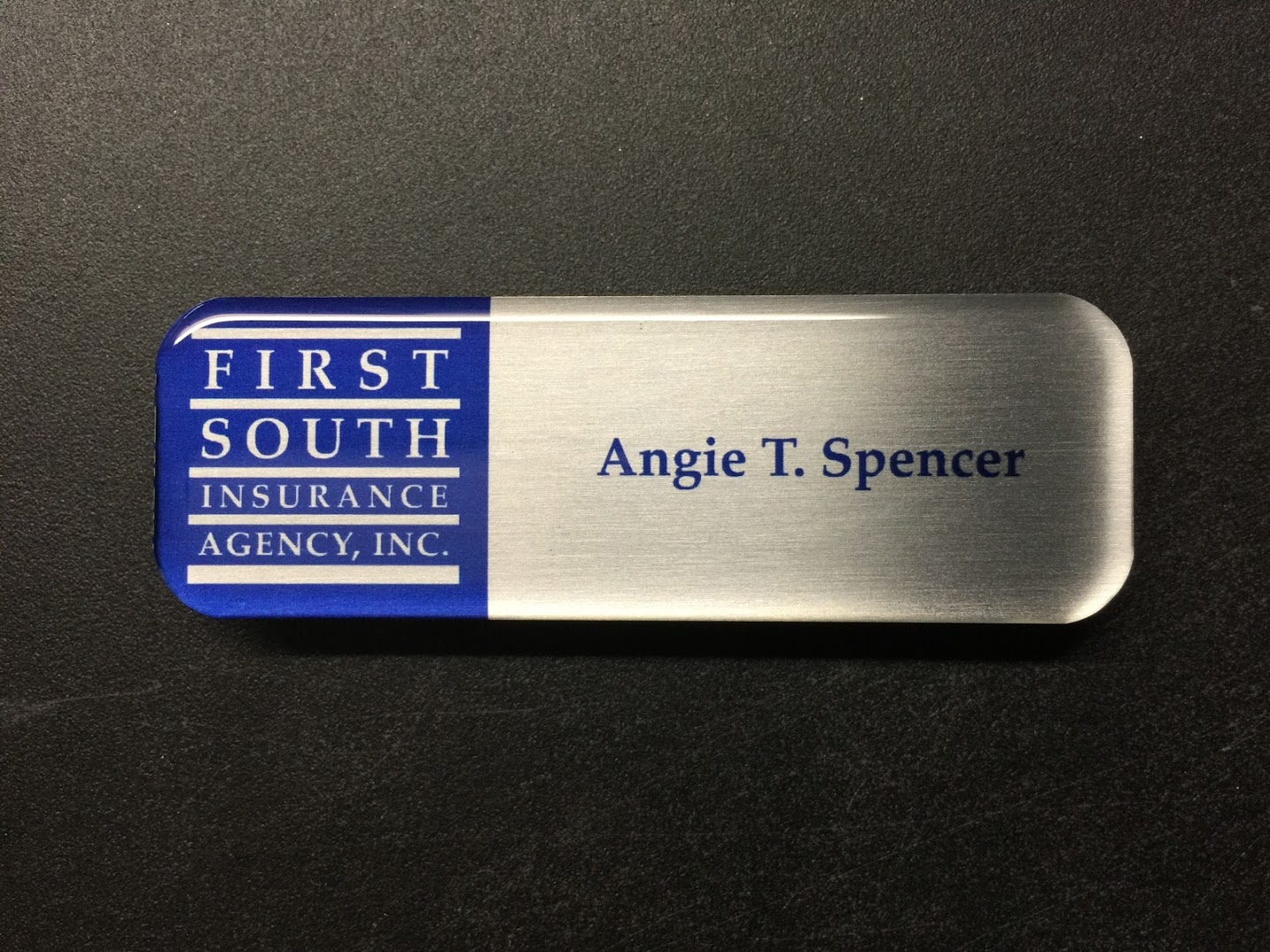 A brushed silver nametag with epoxy coating. Design is for First South Insurance Agency, Inc.
