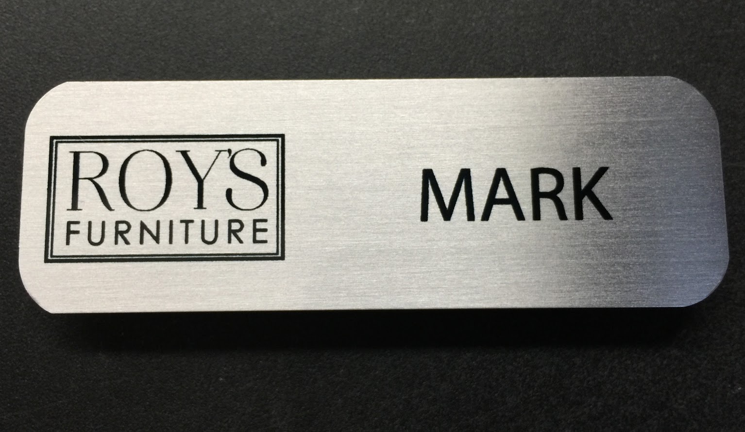 Brushed silver nametag. Design is for Roy's Furniture.