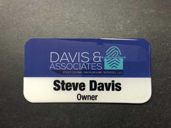 A white metal nametag with epoxy dome coating. Design is for Davis and Associates.